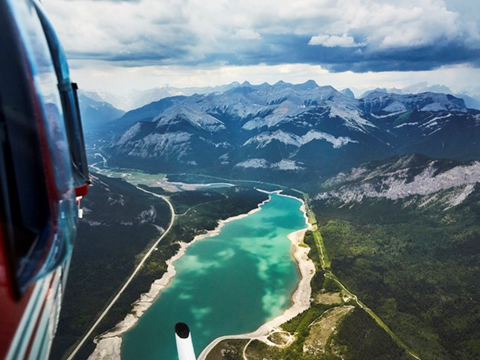 View from a helicopter as the flight soars over glacial fed waters and peaks of the Canadian Rocky Mountains close to Banff and Canmore, Alberta
