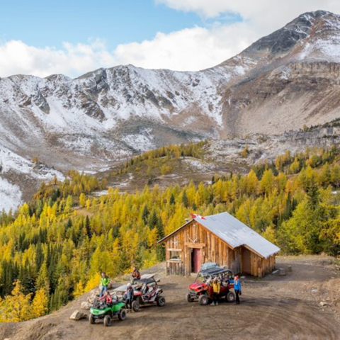 ATVs parked at an historic cabin at the base of a mountain range, the closest ATV experience to Banff and Canmore, Alberta