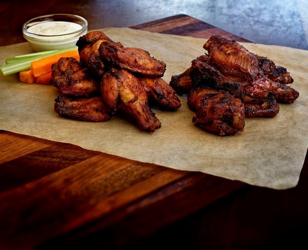 A platter of dry ribbed chicken wings with a dip on the side along with sliced carrots and celery.  The dining feature on Wednesdays at Fergus and Bix in Canmore, Alberta