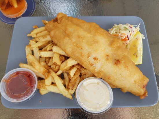 A plate of Fish N' Chips served with a side of coleslaw, lemon wedge, ketchup and tartar sauce.  Found at Sandtraps in Canmore, Alberta