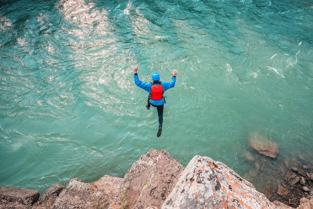 Person jumping off a cliff into the blue water below